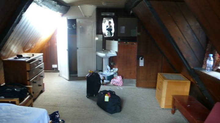 The attic room at Harris Manchester College, Oxford, 2010 — sloped beams, suitcases on the floor, a small sink