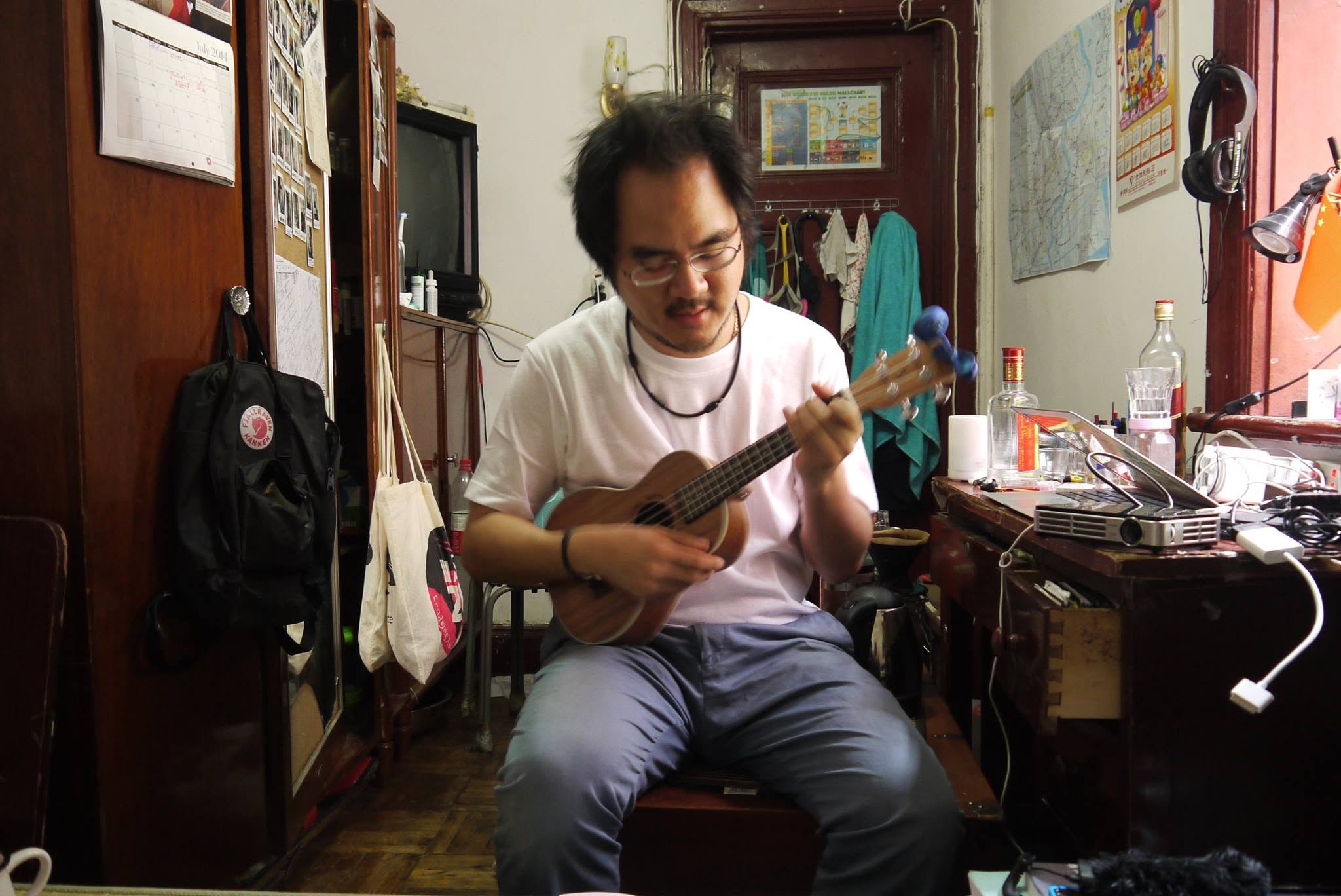 A lilong flat in Yangpu District, Shanghai, 2015 — playing a ukulele between fieldwork, a city map on the wall